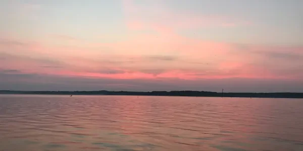 Pink and lavender evening sky reflected on the calm water of Lake Palestine